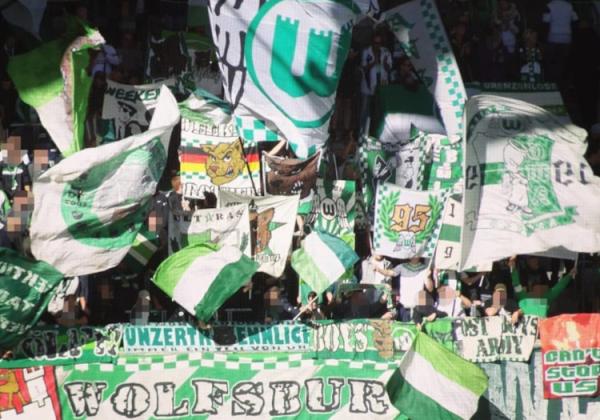 VfL Wolfsburg-Fans mit Fahnen und Doppelhaltern hinterm "Wolfsburg"-Banner