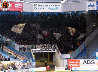 FC St. Pauli-Fans mit Schwenk- und Zaunfahnen im Gästeblock in Rostock.