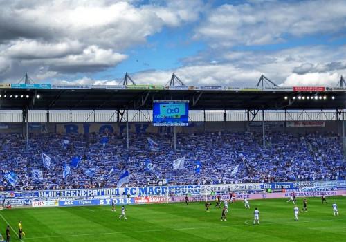 FCM-Fans halten im Heinz-Krügel-Stadion ihre Schals hoch und schwenken Fahnen.