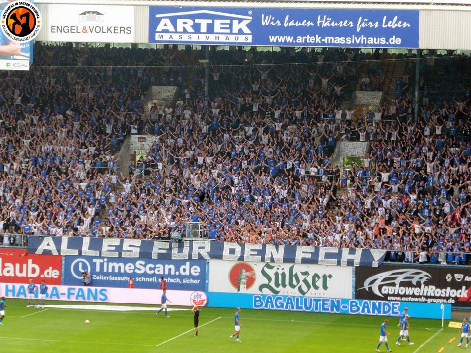 Hansa-Fans am 27.07.2021 mit ausgestreckten Händen auf der vollen Südtribüne Rostock.