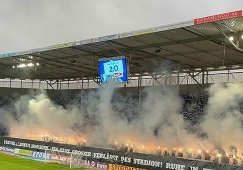 Pyrotechnik hinter "„Freund, Clubfan, Hooligan - Ein ganz Großer verlässt das Stadion! Ruhe in Frieden, Chrissi!"-Spruchband.
